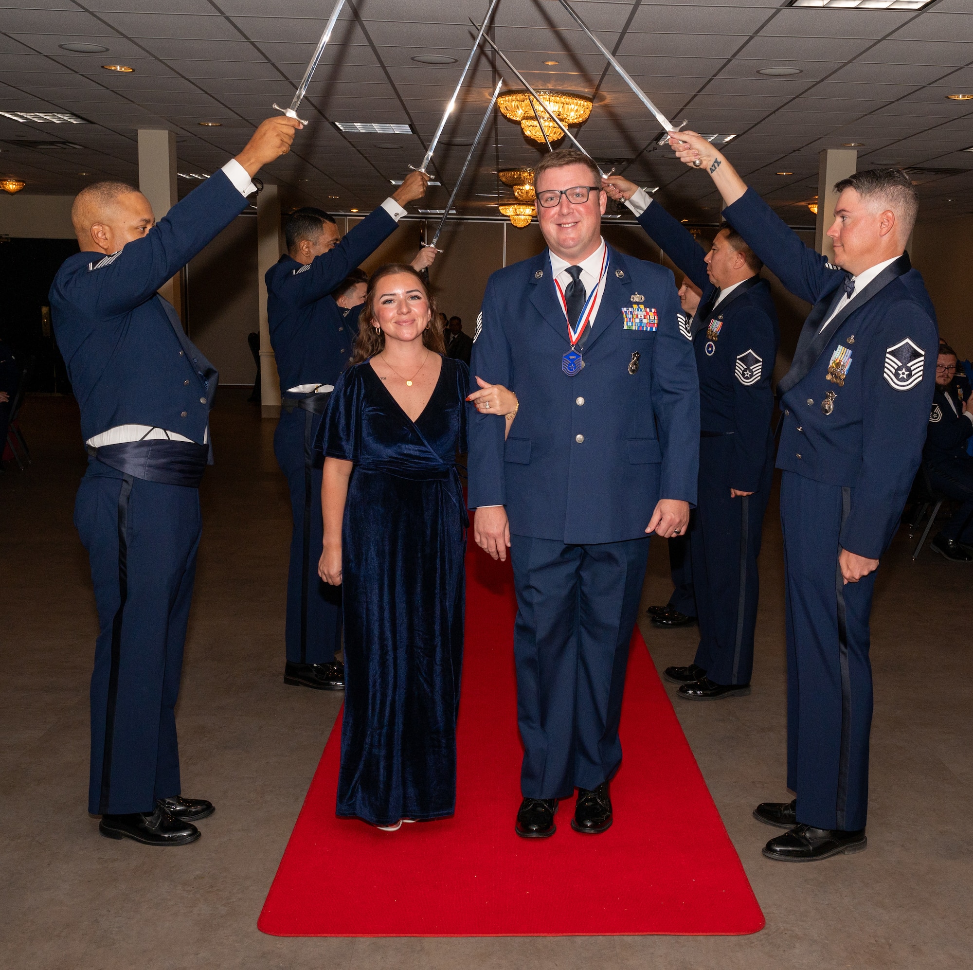 U.S. Air Force (M)Sgt Joshua Botto, 47th Security Forces Squadron, walks under the Saber Team's swords during the senior non-commissioned officer induction ceremony at Laughlin Air Force Base, Texas, Sept. 27, 2024. The induction ceremony brings Airmen together to celebrate the achievement of entering the realm of senior enlisted leaders. (U.S. Air Force photo by Staff Sgt. Nicholas Larsen)
