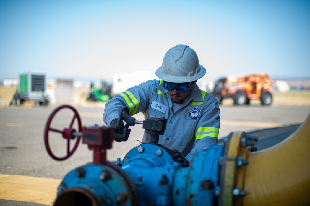 a worker installs a fitting to a valve wheel for a temporary lake