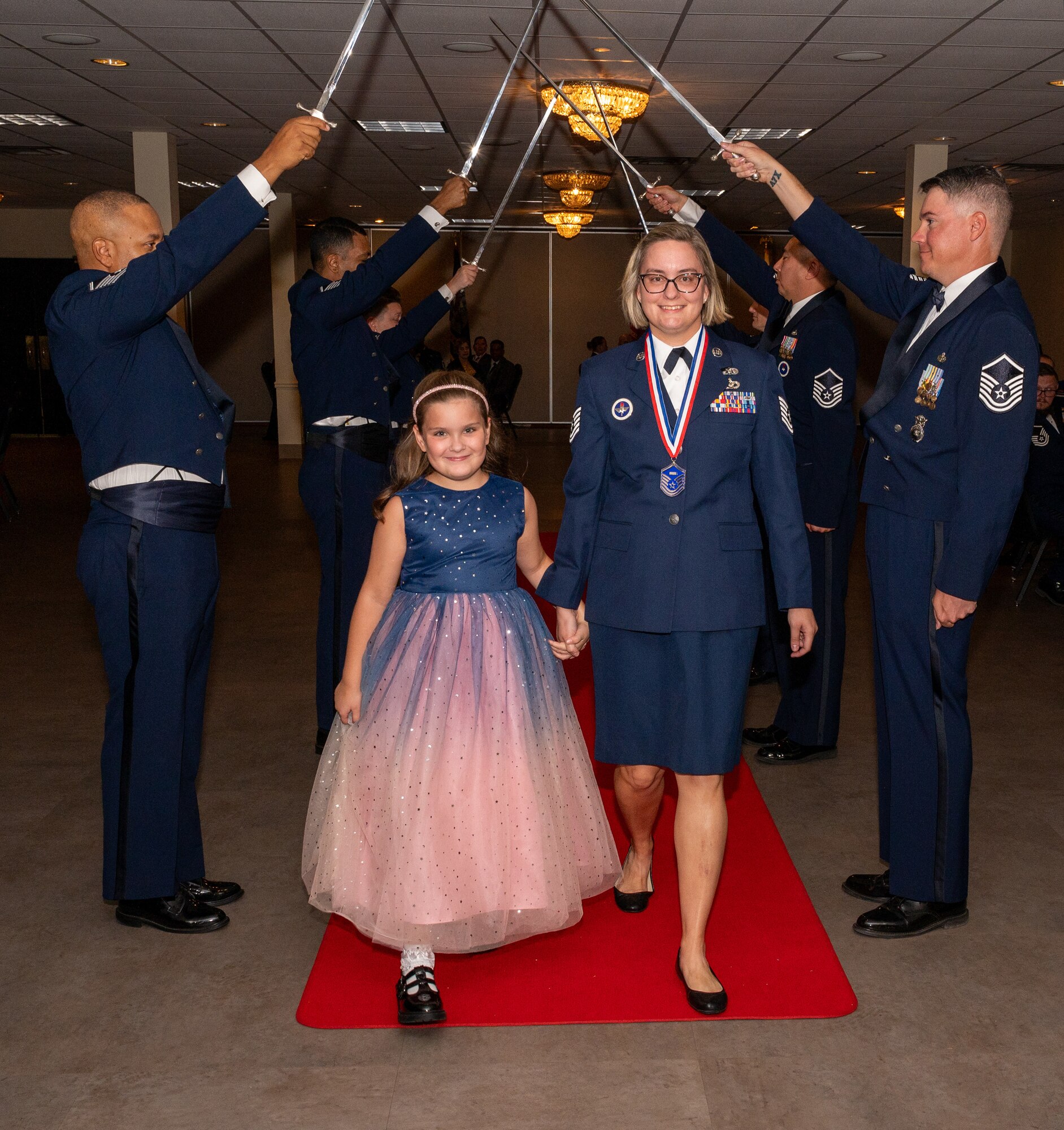 U.S. Air Force (M)Sgt Stefanie Nakoneczny, 47th Civil Engineering Squadron, walks under the Saber Team's swords during the senior non-commissioned officer induction ceremony at Laughlin Air Force Base, Texas, Sept. 27, 2024. The induction ceremony brings Airmen together to celebrate the achievement of entering the realm of senior enlisted leaders. (U.S. Air Force photo by Staff Sgt. Nicholas Larsen)