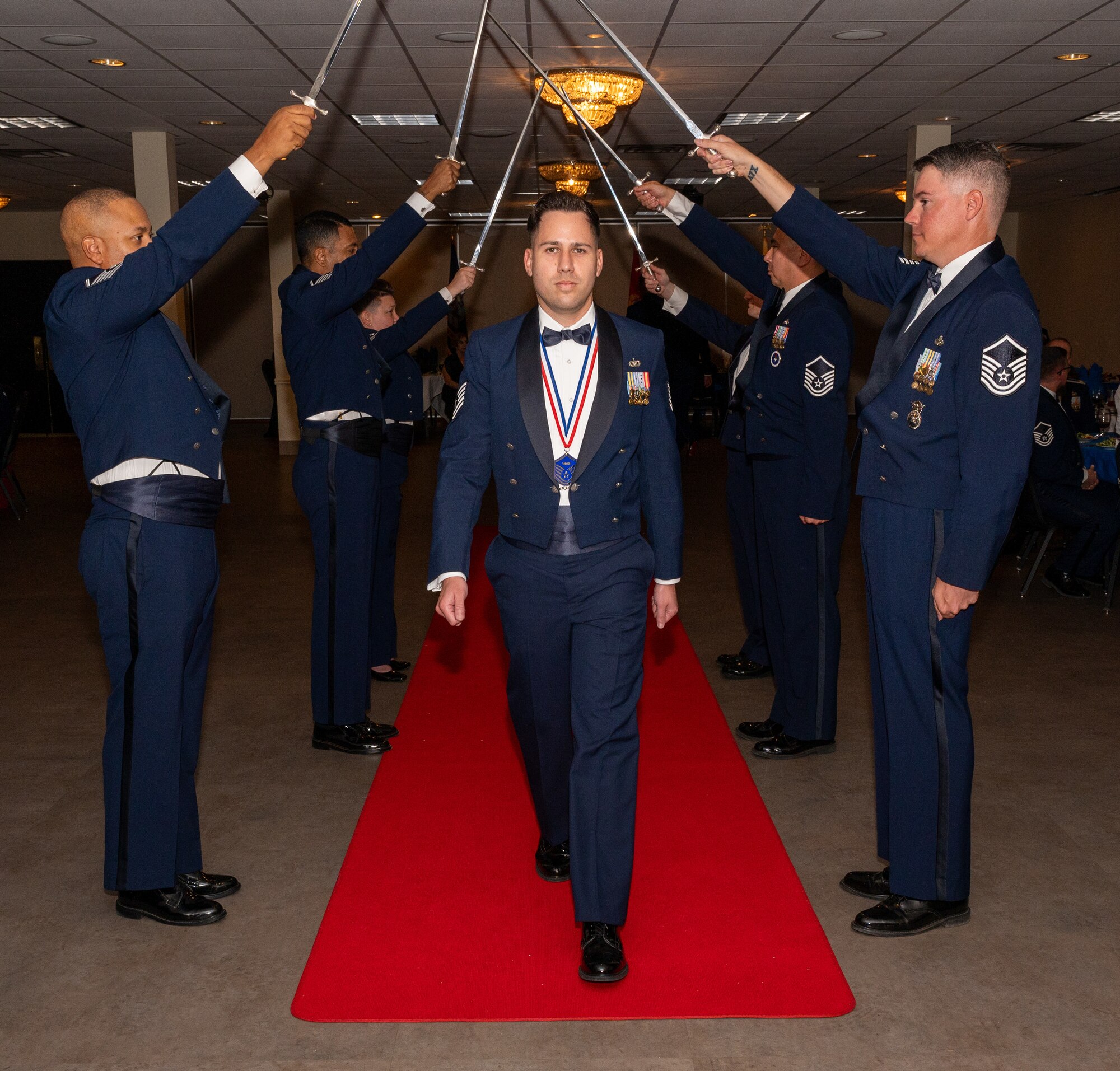 U.S. Air Force (M)Sgt David Vazquez Velez, 47th Operations Support Squadron, walks under the Saber Team's swords during the senior non-commissioned officer induction ceremony at Laughlin Air Force Base, Texas, Sept. 27, 2024. The induction ceremony brings Airmen together to celebrate the achievement of entering the realm of senior enlisted leaders. (U.S. Air Force photo by Staff Sgt. Nicholas Larsen)