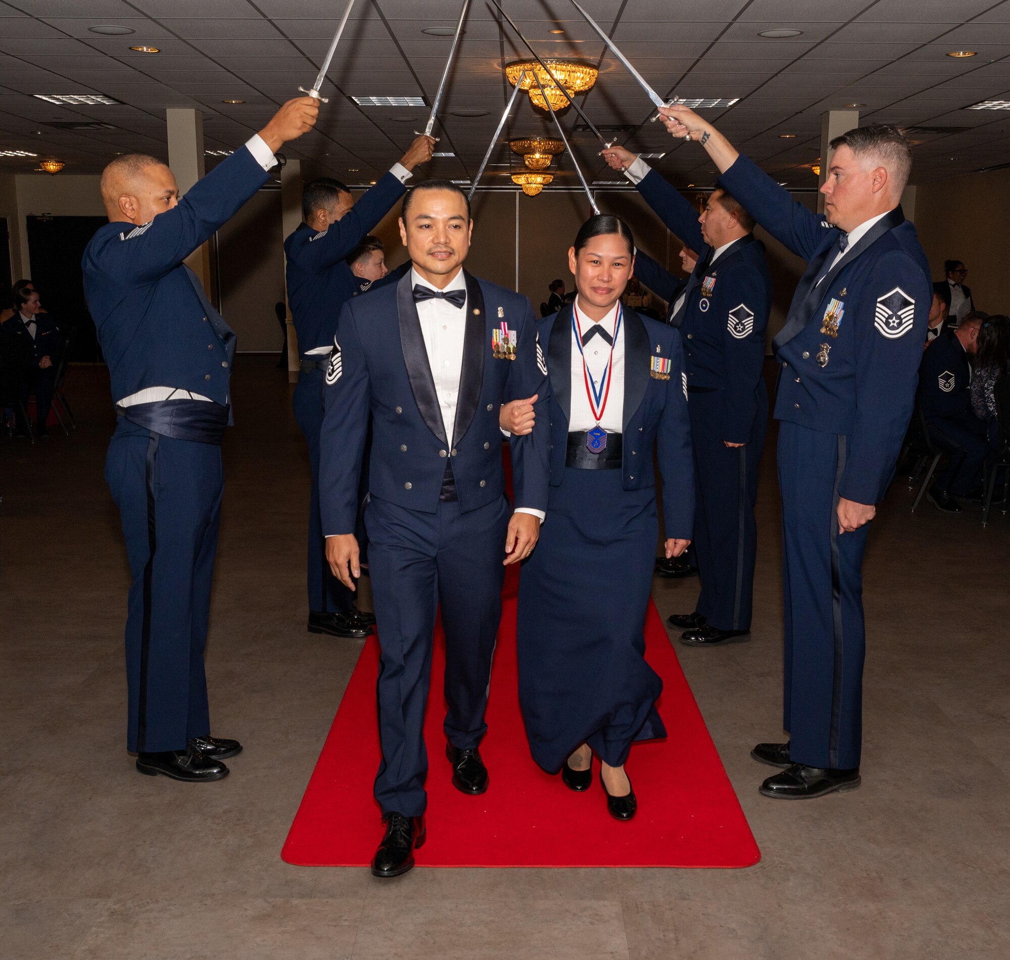 U.S. Air Force (M)Sgt Jasmine Pabalan, 47th Medical Group, walks under the Saber Team's swords during the senior non-commissioned officer induction ceremony at Laughlin Air Force Base, Texas, Sept. 27, 2024. The induction ceremony brings Airmen together to celebrate the achievement of entering the realm of senior enlisted leaders. (U.S. Air Force photo by Staff Sgt. Nicholas Larsen)