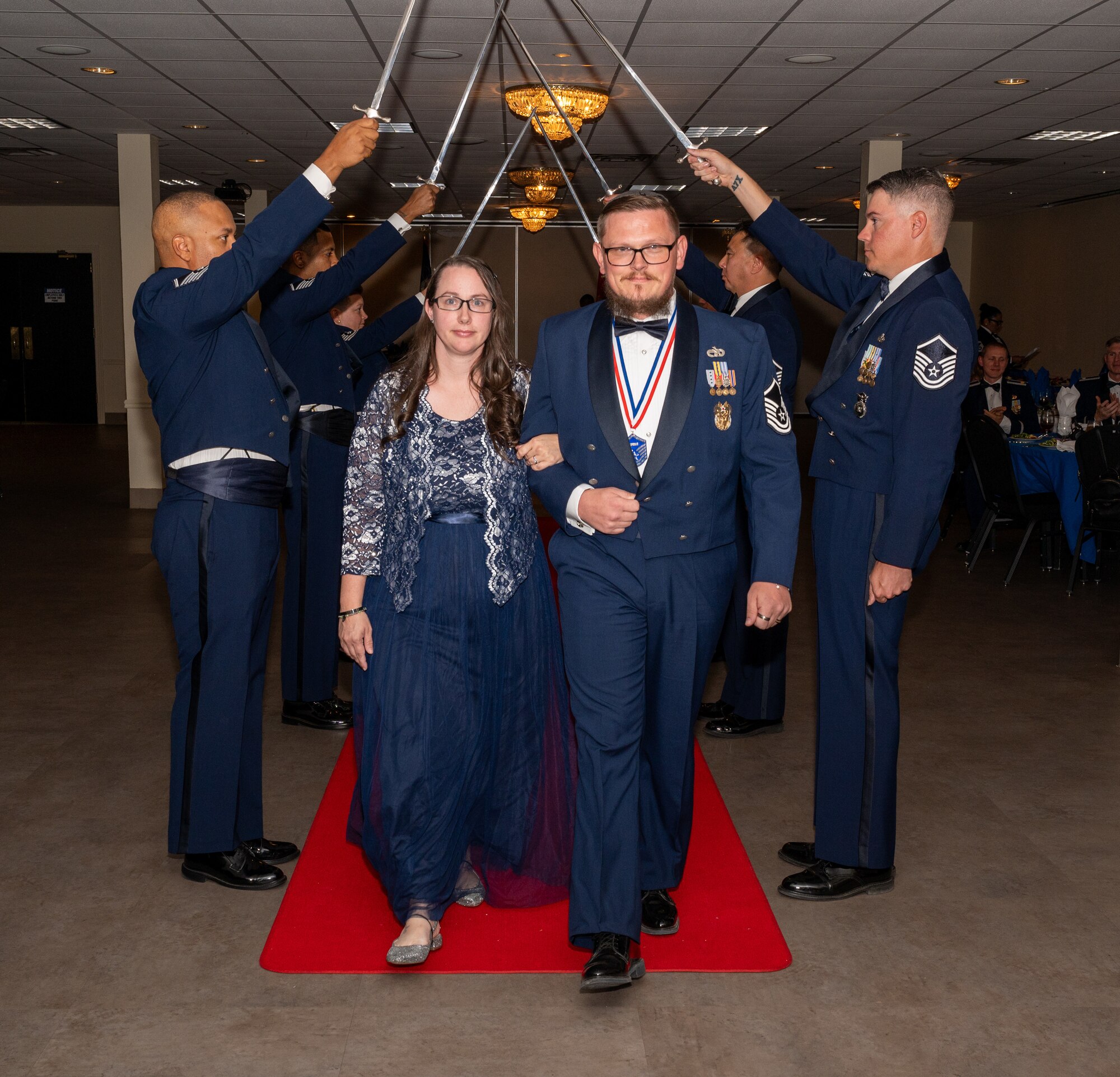 U.S. Air Force MSgt Seth Mihalik, 47th Inspector General’s Office, walks under the Saber Team's swords during the senior non-commissioned officer induction ceremony at Laughlin Air Force Base, Texas, Sept. 27, 2024. The induction ceremony brings Airmen together to celebrate the achievement of entering the realm of senior enlisted leaders. (U.S. Air Force photo by Staff Sgt. Nicholas Larsen)