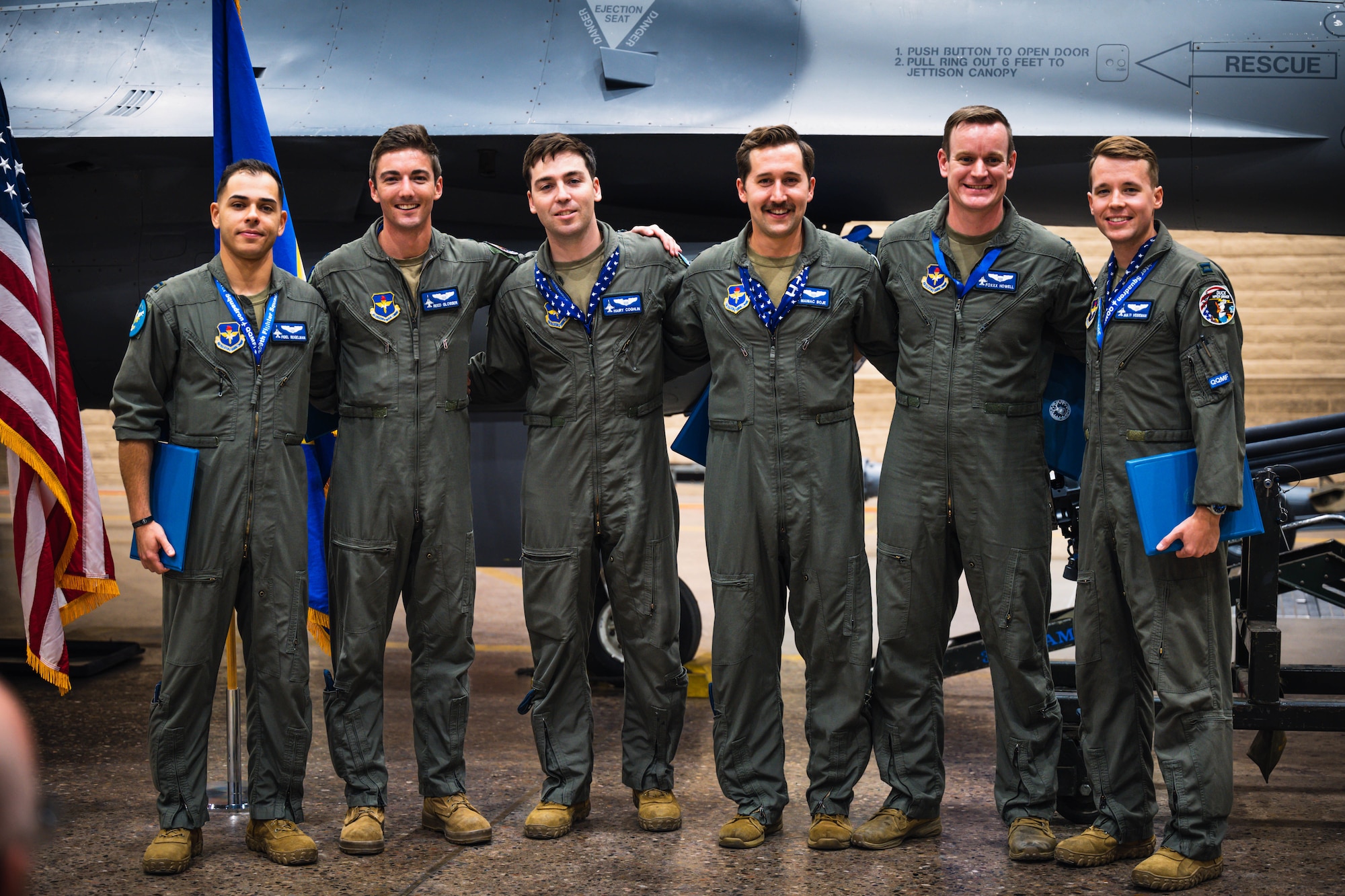 U.S. Air Force graduated pilots pose for a photo in front of an F-16 Fighting Falcon, assigned to the 309th Fighter Squadron, during the final 309th FS graduation for F-16 pilots.