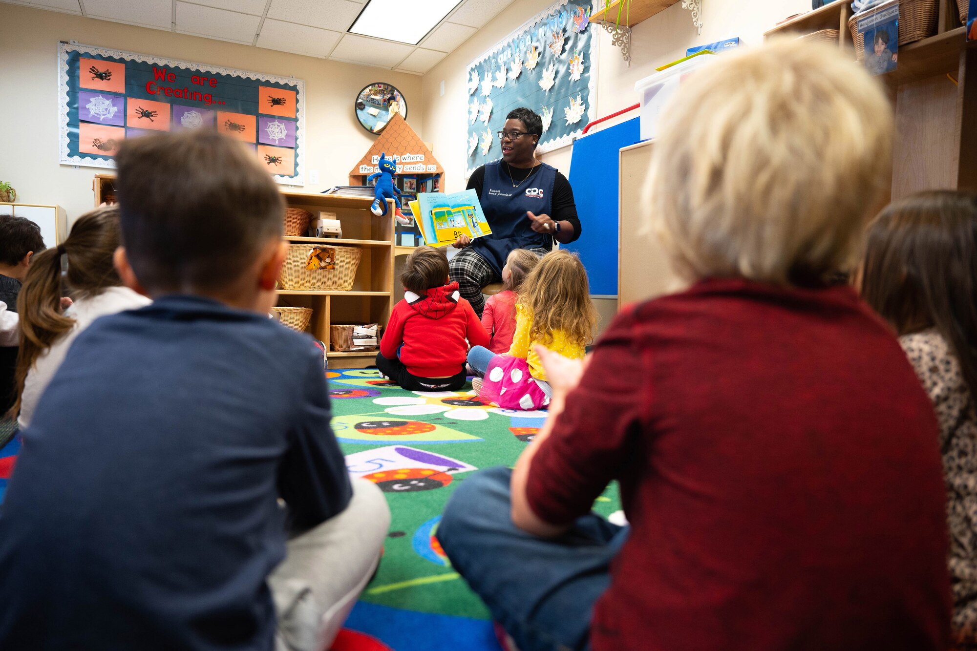 A woman reads a book to a group of children.