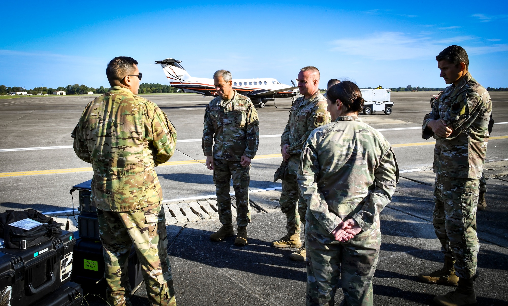 Individuals chat about equipment on a flight line.