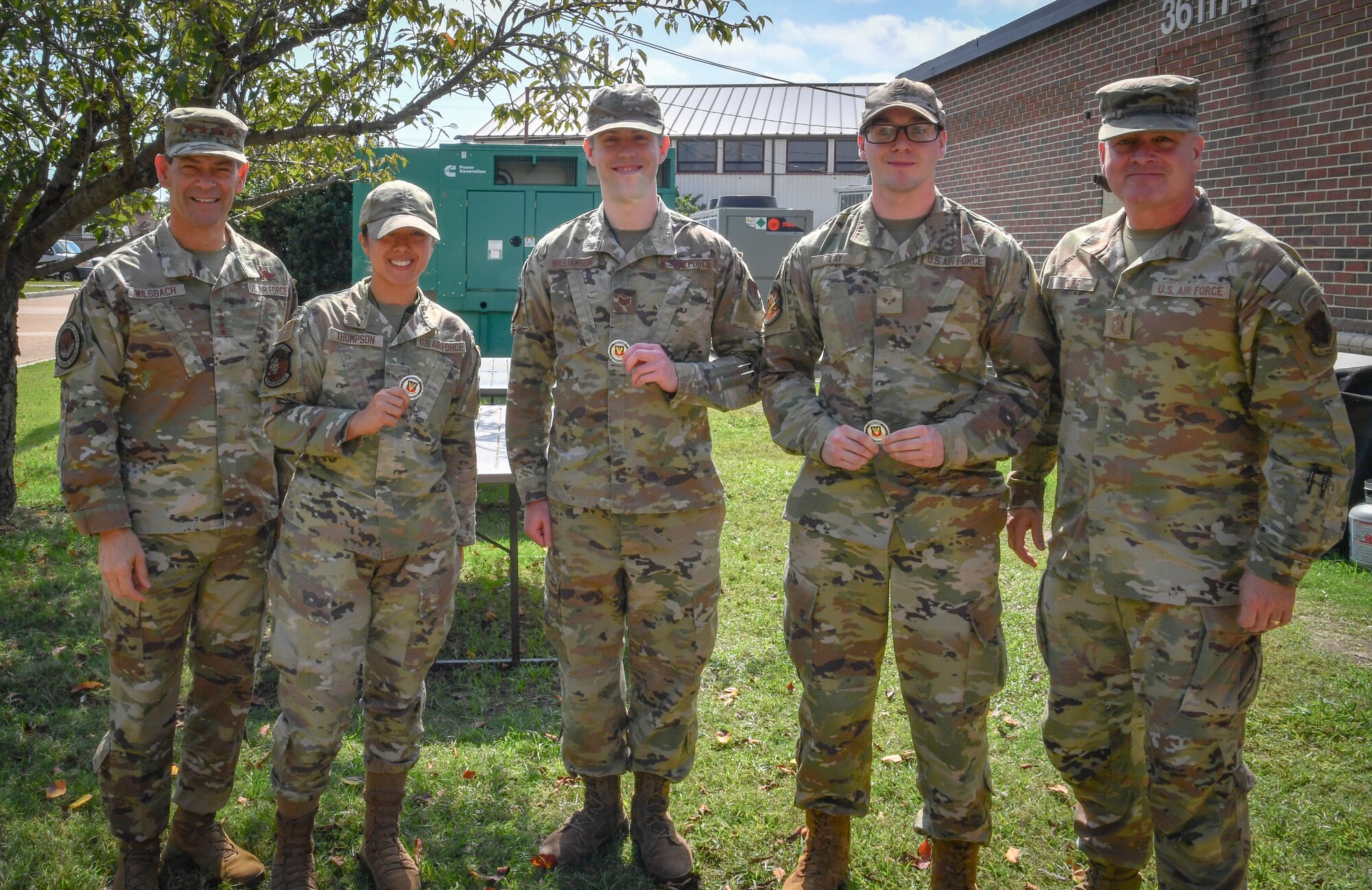 Individuals pose for a group photo holding their coins.