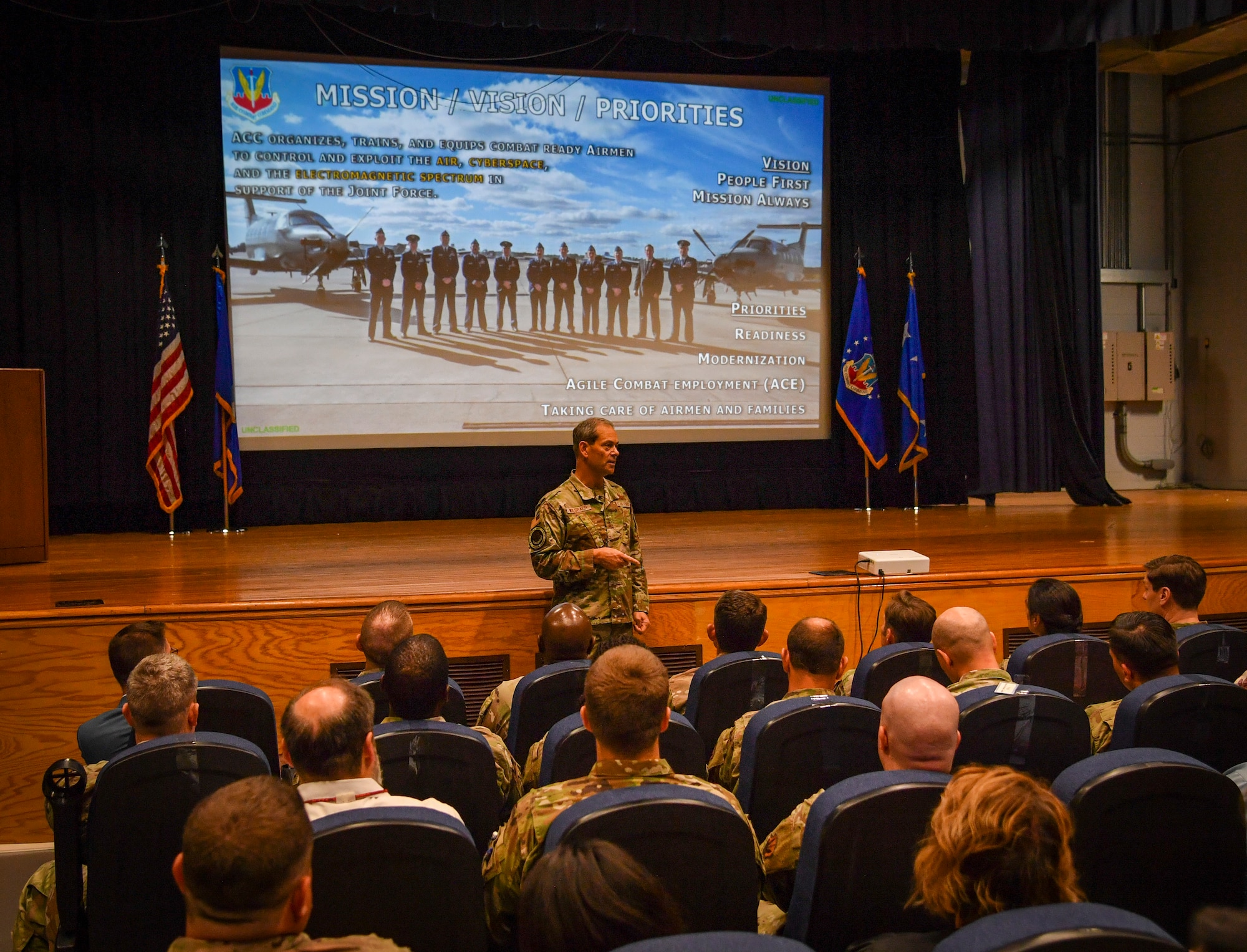 An individuals speaks to a room full of people sitting down.