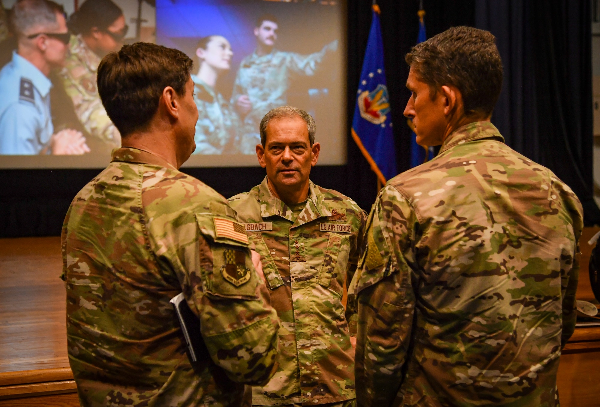 A group of three individuals talk to each other.