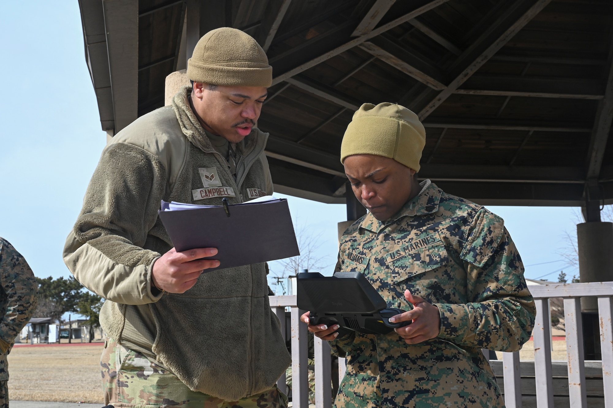 Senior Airman Marcus Campbell, left, 8th Security Forces Squadron counter small unmanned aircraft system and sUAS trainer, instructs U.S. Marine Corps Sgt. Cyan Williams, an electrician with Marine Wing Support Squadron 172, Marine Aircraft Group 36, 1st Marine Aircraft Wing, on piloting a small unmanned aircraft system.