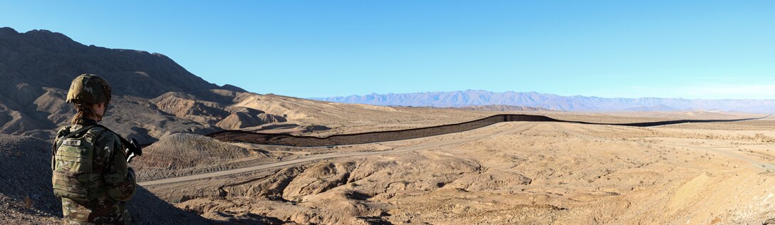 A soldier looks out at a barren, sandy plain.