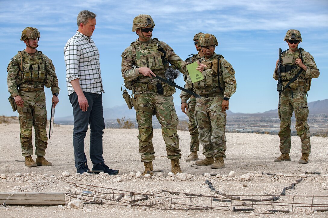 Five soldiers in tactical gear speak to a person outside.