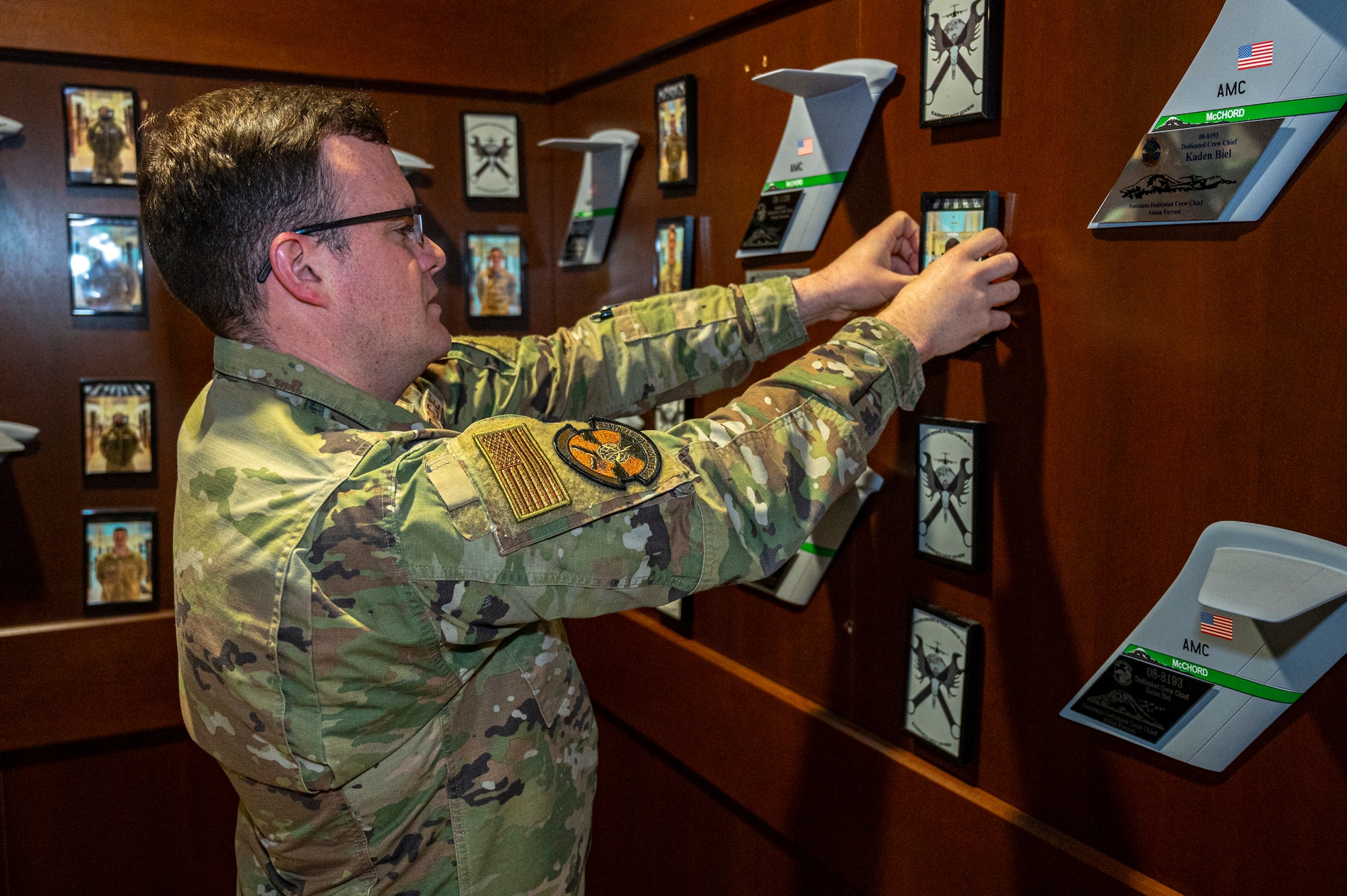 U.S. Air Force Staff Sgt. Joshua Davids, 62d Aircraft Maintenance Squadron dedicated crew chief, puts up an Airman’s photo on the DCC wall outside of the 62d Aircraft Maintenance Squadron’s Silver Aircraft Maintenance Unit shop at Joint Base Lewis-McChord, Washington, March 26, 2025.