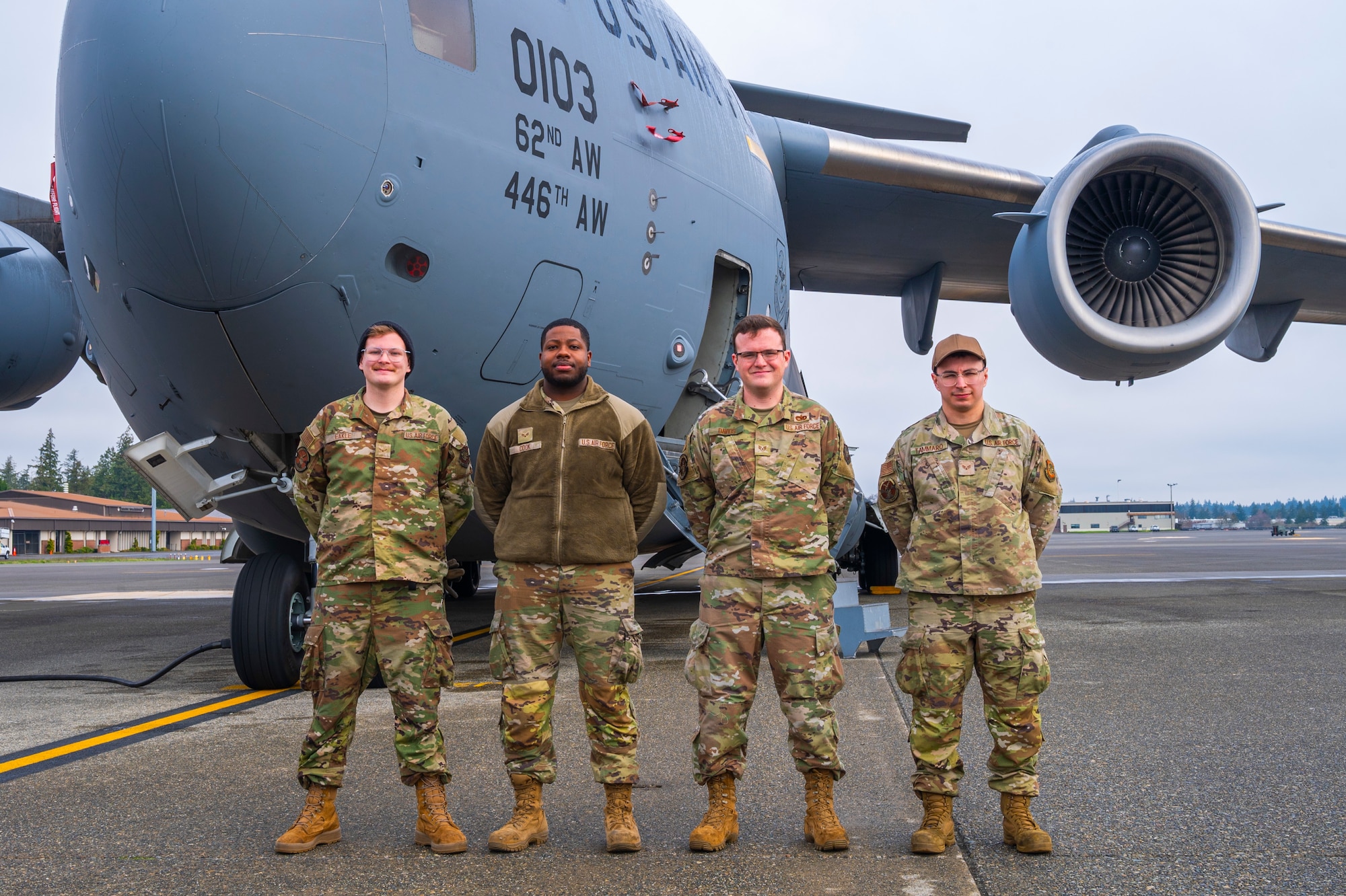 U.S. Air Force Airman First Class Jacob Eakle, Senior Airman David Cook, Staff Sgt. Joshua Davids, and Senior Airman Joseph Tammaro, respectively, all 62d Aircraft Maintenance Squadron dedicated crew chiefs or assistant dedicated crew chiefs, stand in front of a C-17 Globemaster III at Joint Base Lewis-McChord, Washington, March 26, 2025.