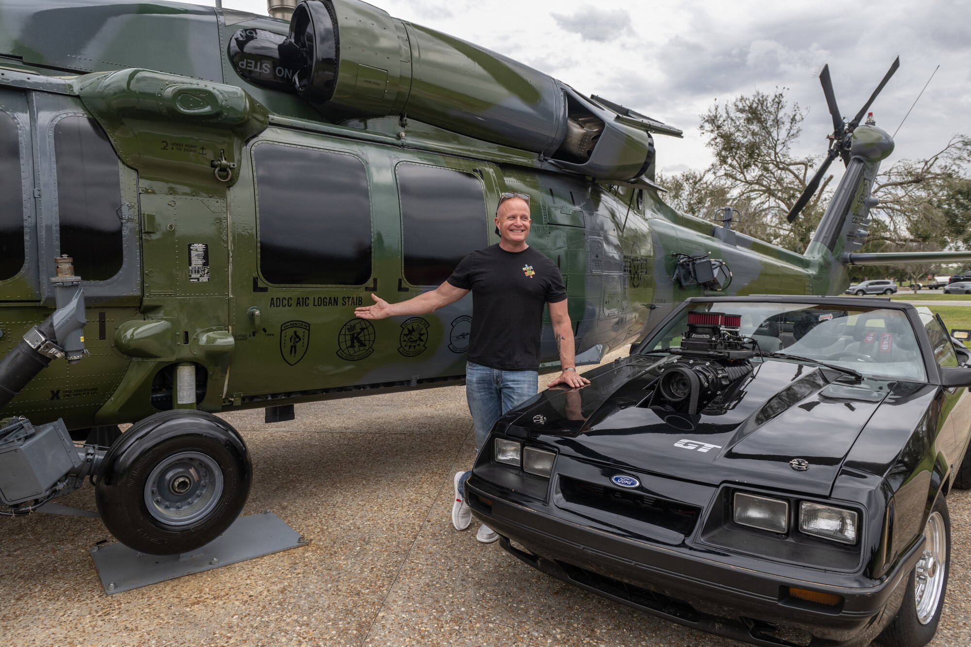 A man stands between a HH-60 and a Mustang.