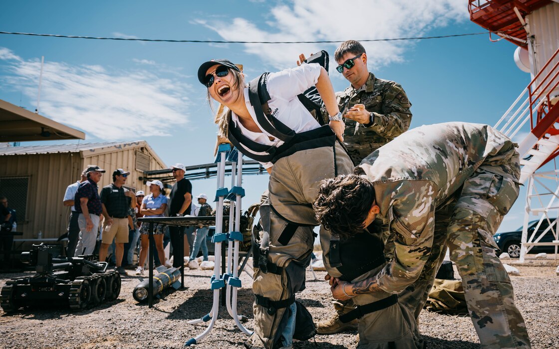 U.S. Air Force Airmen from the Explosive Ordnance Disposal flight assigned to the 56th Civil Engineer Squadron puts an EOD bomb suit on a community leader.