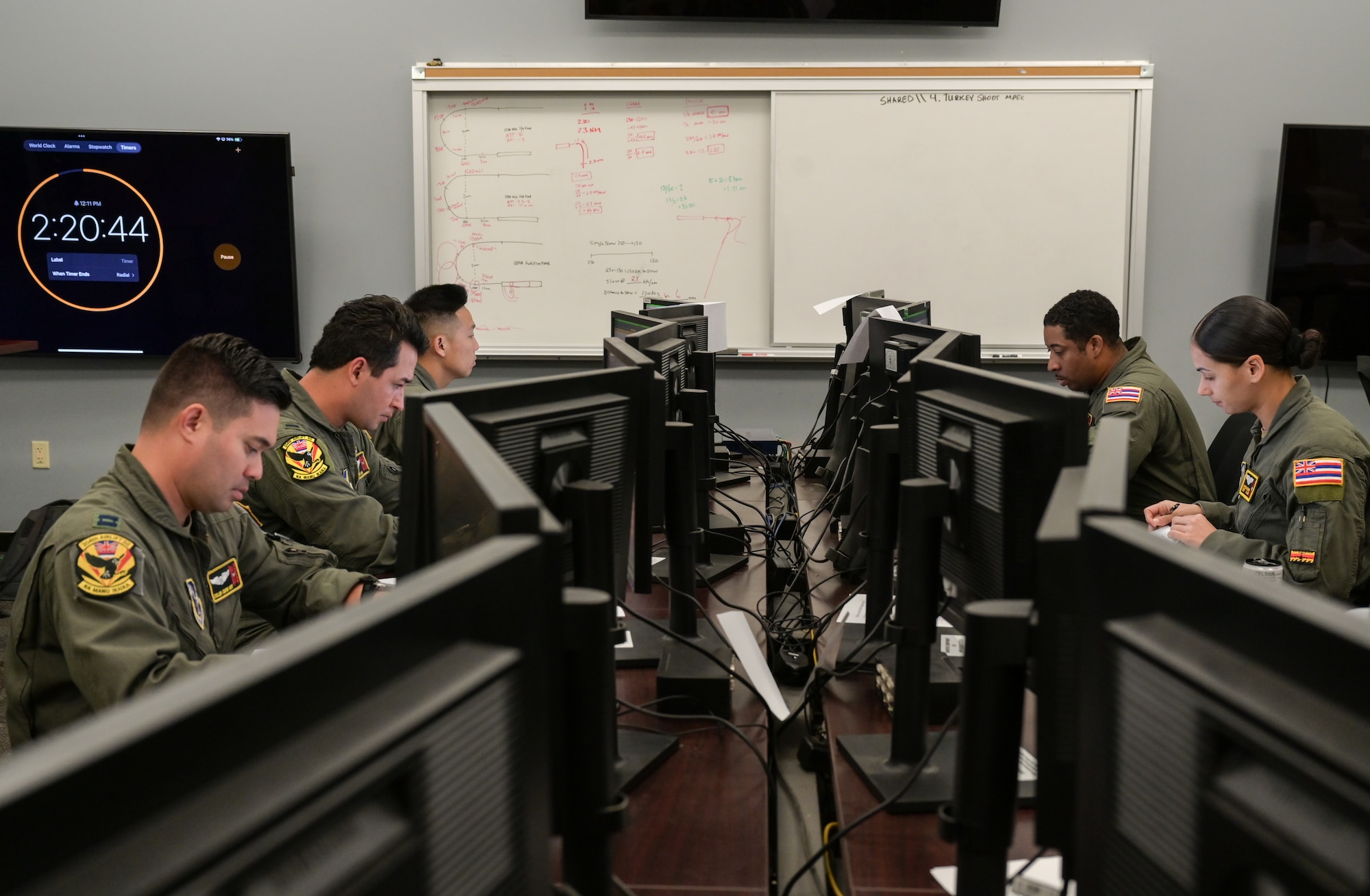 Five Airmen work on computers.