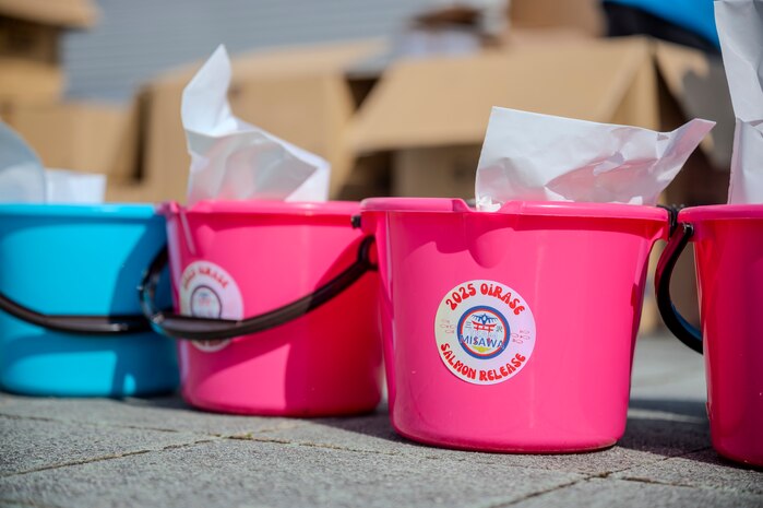 Buckets provided by the 35th Force Support Squadron, used to release juvenile salmon into the riverbank, rest on the ground near the Oirase Shimoda Salmon Park at Oirase, Japan, March 15, 2025.