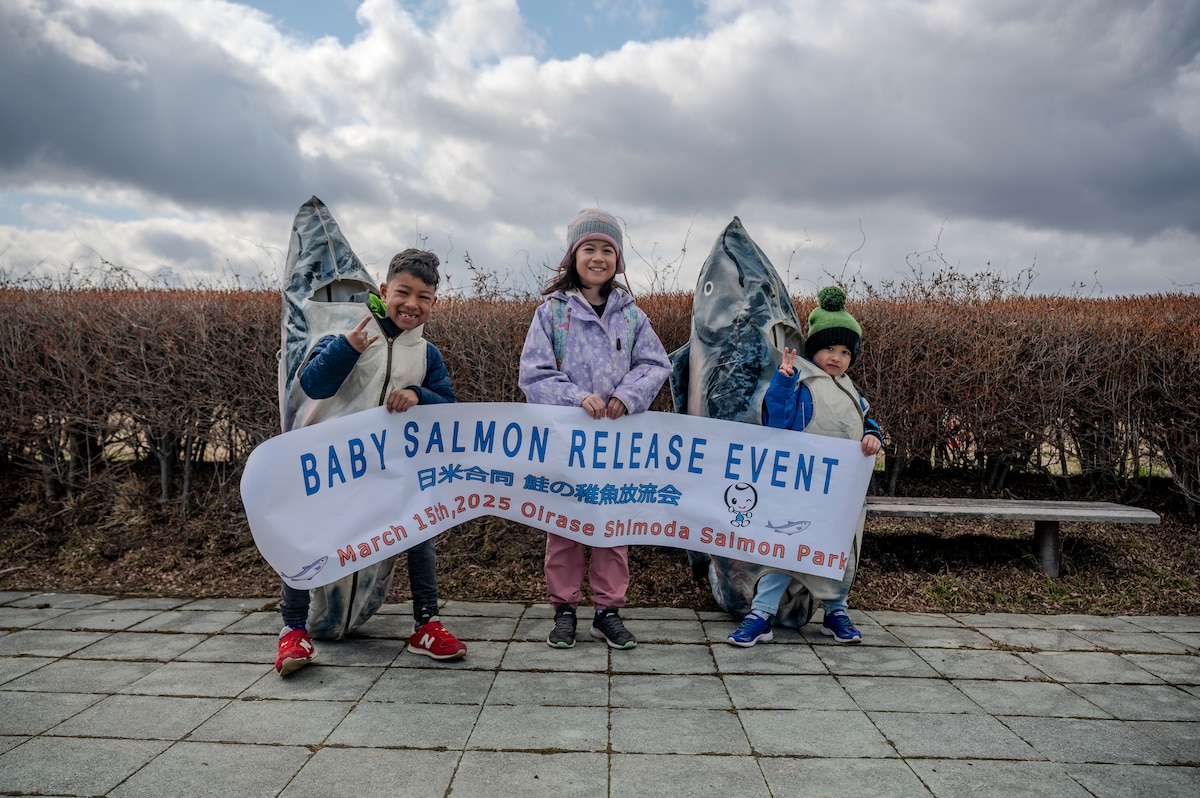 Children pose with a sign for the 26th Annual Oirase Salmon Release near the Oirase Shimoda Salmon Park at Oirase, Japan, March 15, 2025.