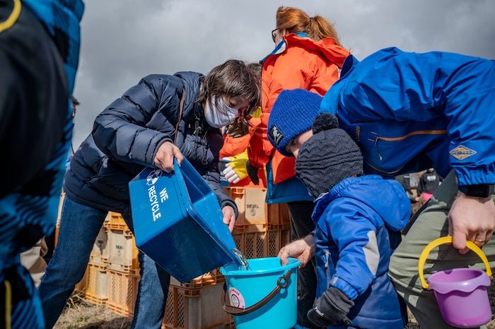 Families fill their buckets with juvenile salmon before releasing them during the 26th Annual Oirase Salmon Release near the Oirase Shimoda Salmon Park at Oirase, Japan, March 15, 2025.