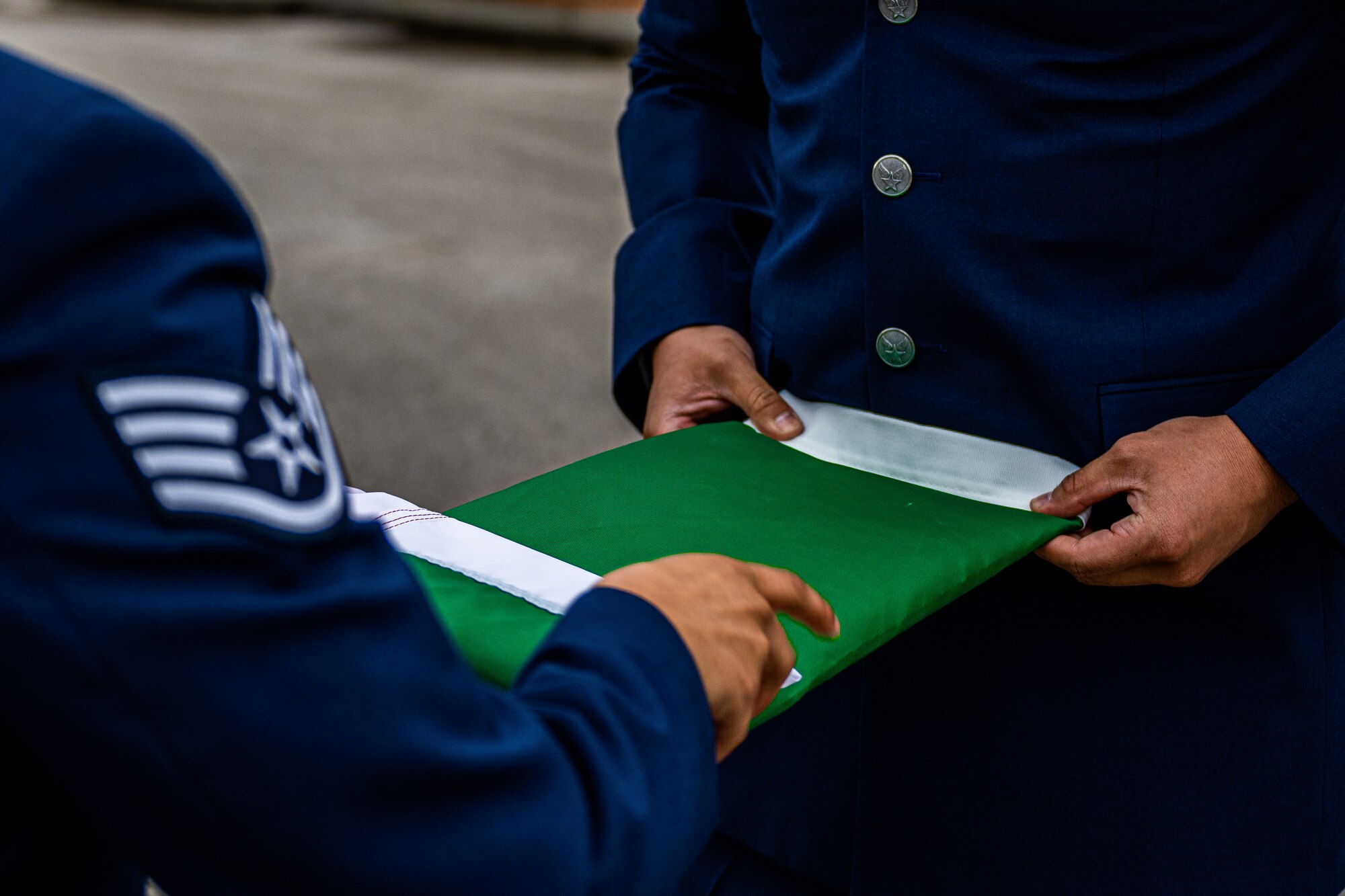 U.S. Air Force Staff Sgt. Yulissa Daniels, 31st Operations Support Squadron weather craftsman, and Tech. Sgt. Matthew Flores, 31st OSS radar, airfield and weather systems NCOIC, fold the Italian flag after retreat.