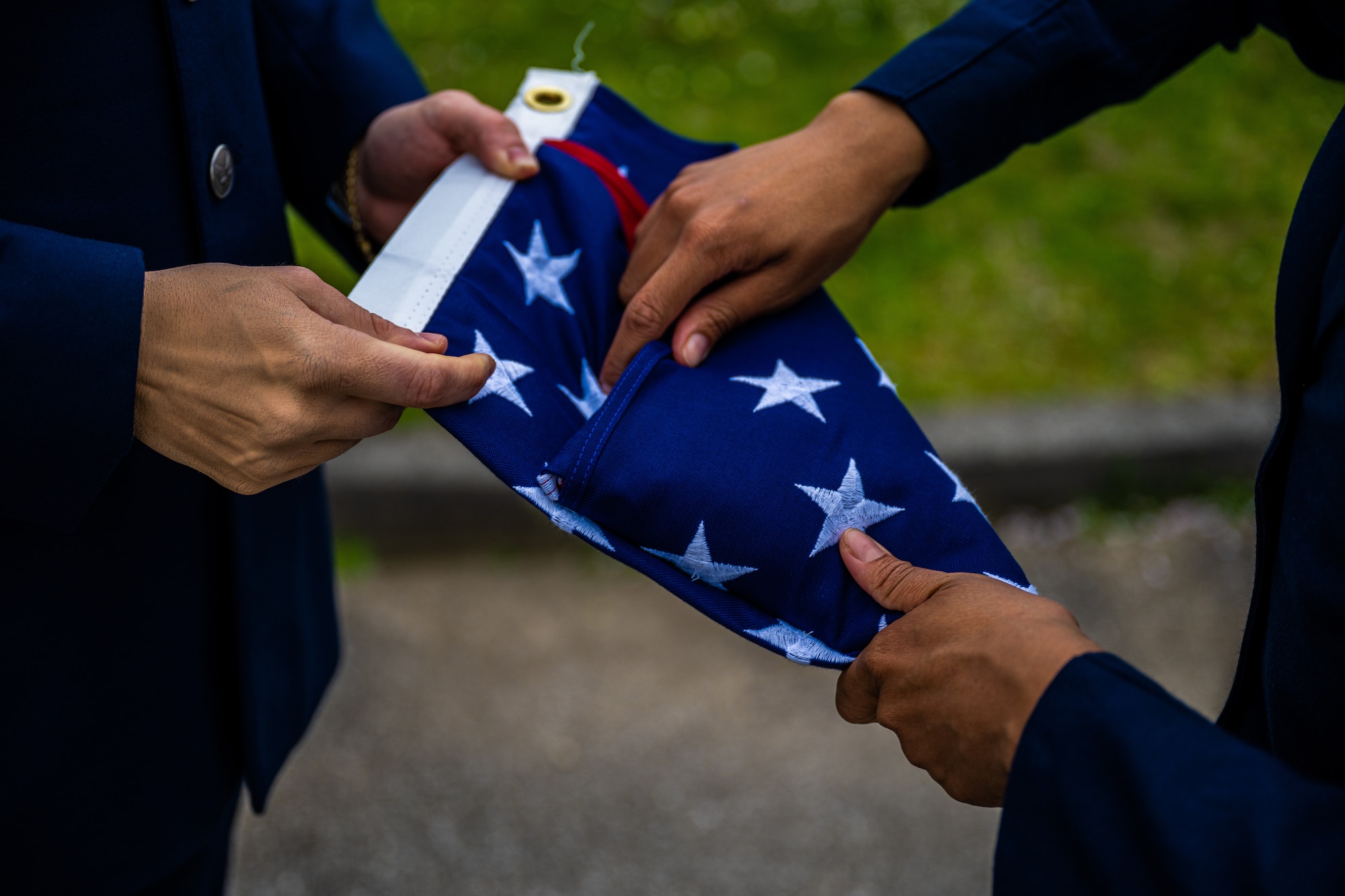 From left, U.S. Air Force Staff Sgt. Blue Rinato, 31st Operations Support Squadron air traffic control tower journeyman, and Airman 1st Class Ava Harris, 31st OSS aircrew flight equipment journeyman, fold the U.S. flag after retreat.