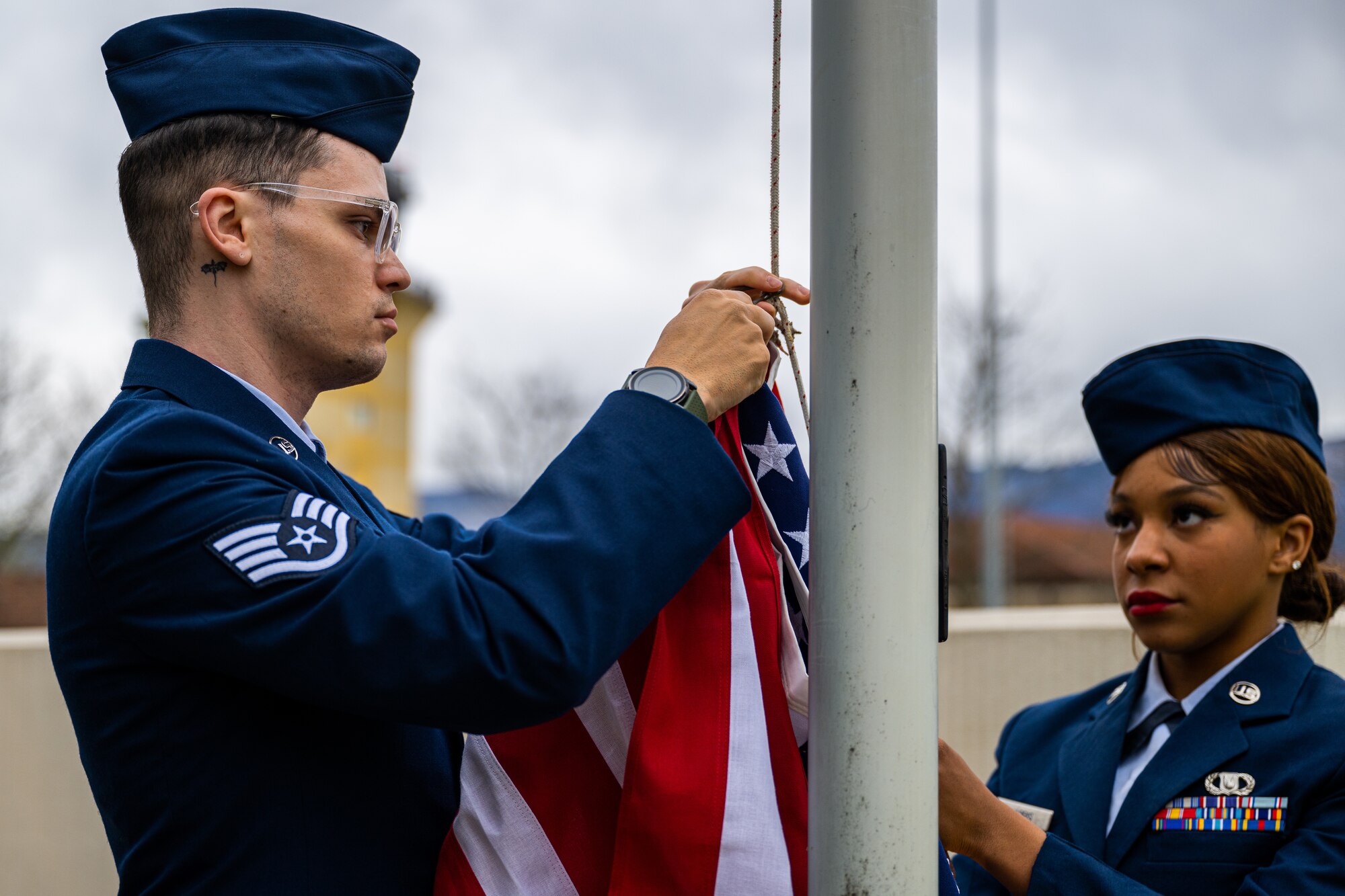 U.S. Air Force Staff Sgt. Blue Rinato, 31st Operations Support Squadron air traffic control tower journeyman, and Airman 1st Class Ava Harris, 31st OSS aircrew flight equipment journeyman, unhook the U.S. flag during retreat.