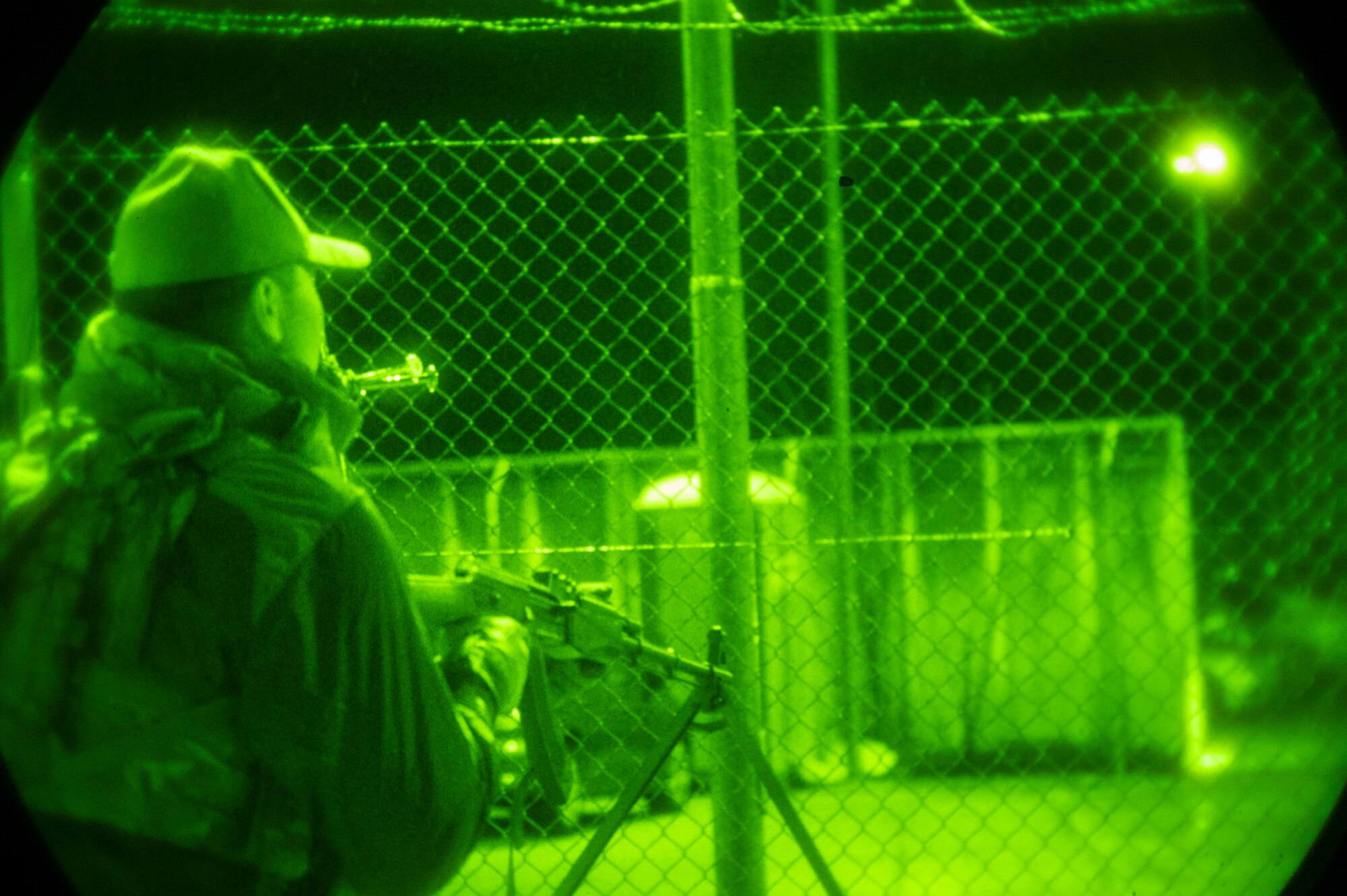An armed Airman peers out into the distance at night