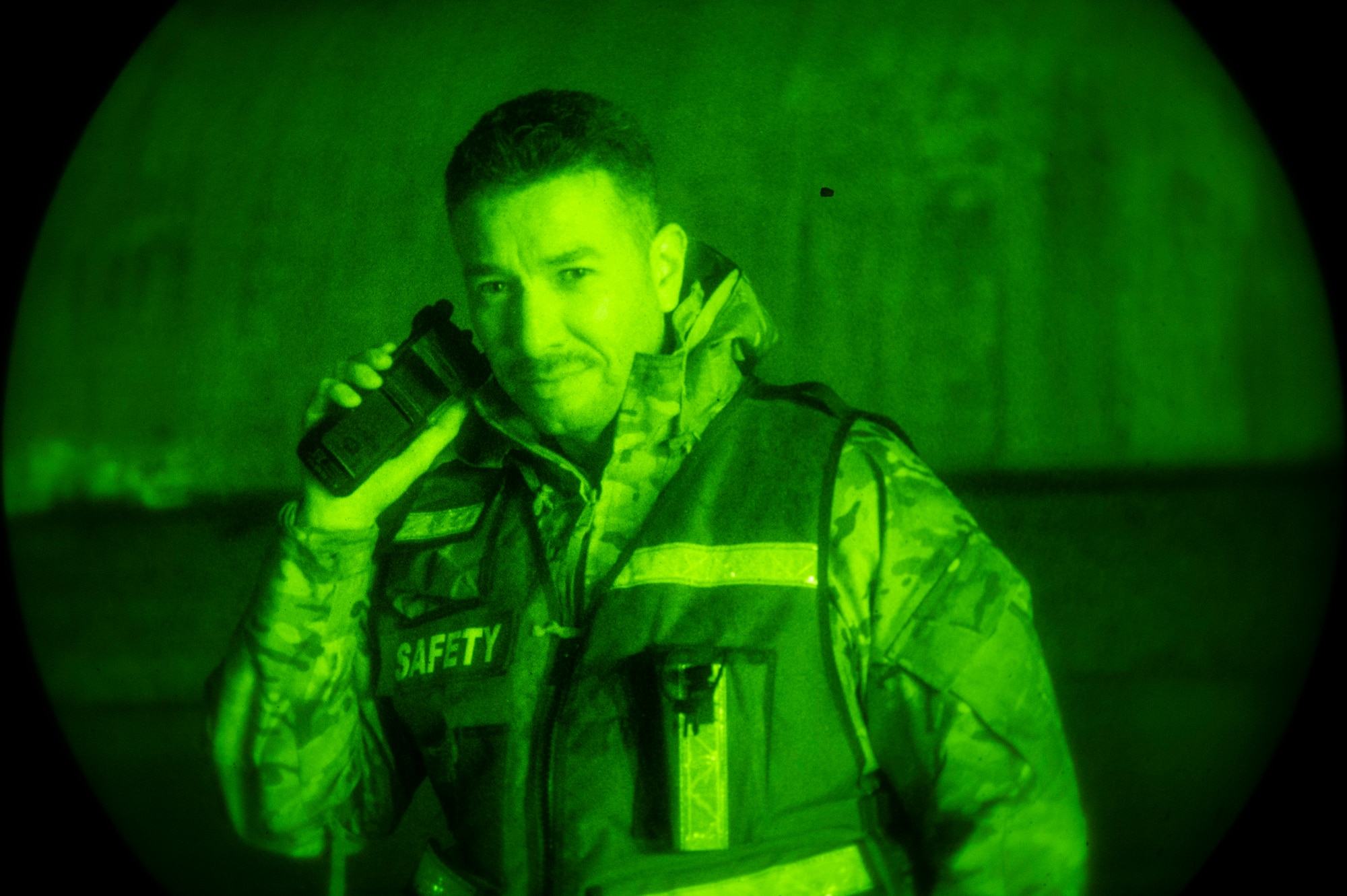 A man speaks into a handheld radio at night