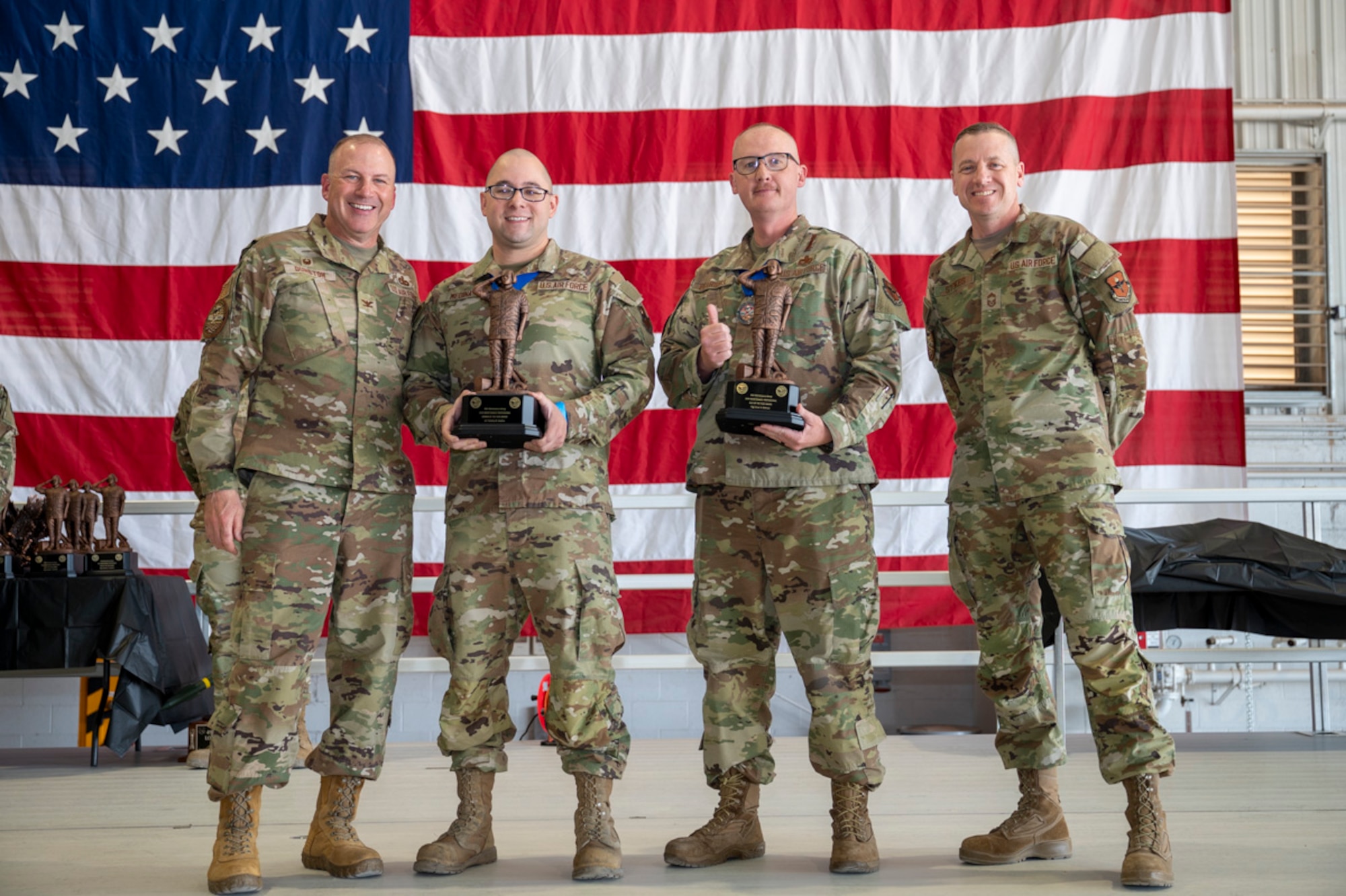 U.S. Air Force Senior Airman Timothy Medina, left center, and U.S. Air Force Master Sgt. Lawrence Pearsall, right center, accept the Maintenance Professional Award from U.S. Air Force Col. Chris Dusnton, 49th Maintenance Group commander and U.S. Air Force Chief Master Sgt. Andrew Stokes, 49th MXG superintendent, at Holloman Air Force Base, New Mexico, March 28, 2025. The original maintenance professional award was established in 1979 to recognize outstanding performance of direct, sortie-producing maintenance specialists, a tradition that recognizes the best maintenance personnel in our profession of arms. (U.S. Air Force photo by Senior Airman Michelle Ferrari)