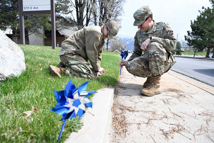 Two airman place pinwheels into the ground