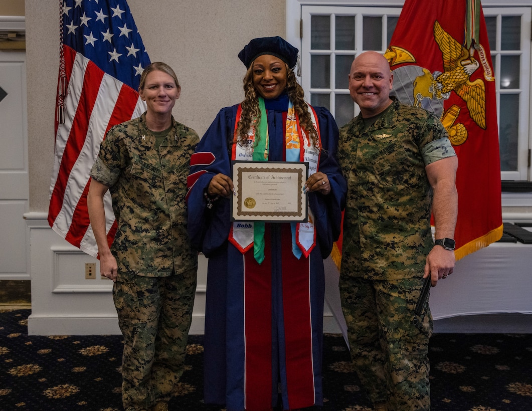 U.S. Marine Corps Col. Jenny Colegate, left, commanding officer, Marine Corps Base Quantico, Jabena Bobb, award recipient, center, and Sgt. Maj. Michael Brown, sergeant major of MCBQ, pose for a group photo during the Celebrating Student Success event at the Clubs at Quantico on MCBQ, Virginia, April 1, 2025. Veterans and active-duty service members were celebrated on their academic accomplishments of completing their formal education despite the daily challenges to meet all requirements called upon them in their personal and professional lives. (U.S. Marine Corps photo by Lance Cpl. Ethan Miller)