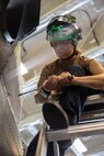 Aviation Structural Mechanic 1st Class Kirstyn Campos, assigned to the "Spartans" of Helicopter Maritime Strike Squadron (HSM) 70, performs maintenance on the fire bottle panel of an MH-60R Sea Hawk aboard the world’s largest aircraft carrier, USS Gerald R. Ford (CVN 78), April 1, 2025.