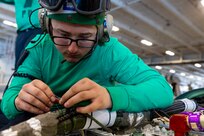 Aviation Electrician's Mate 2nd Class Phillip Newton, assigned to the "Gray Wolves" of Electronic Attack Squadron (VAQ) 142, re-pins the connector in an E/A-18G Growler in the hangar bay of the world's largest aircraft carrier, USS Gerald R. Ford (CVN 78), April 1, 2025.