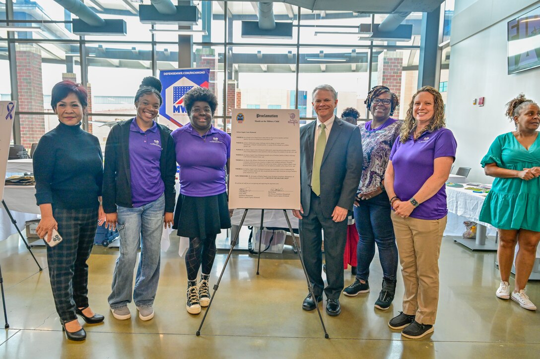 A group of employees stand next to a sign.