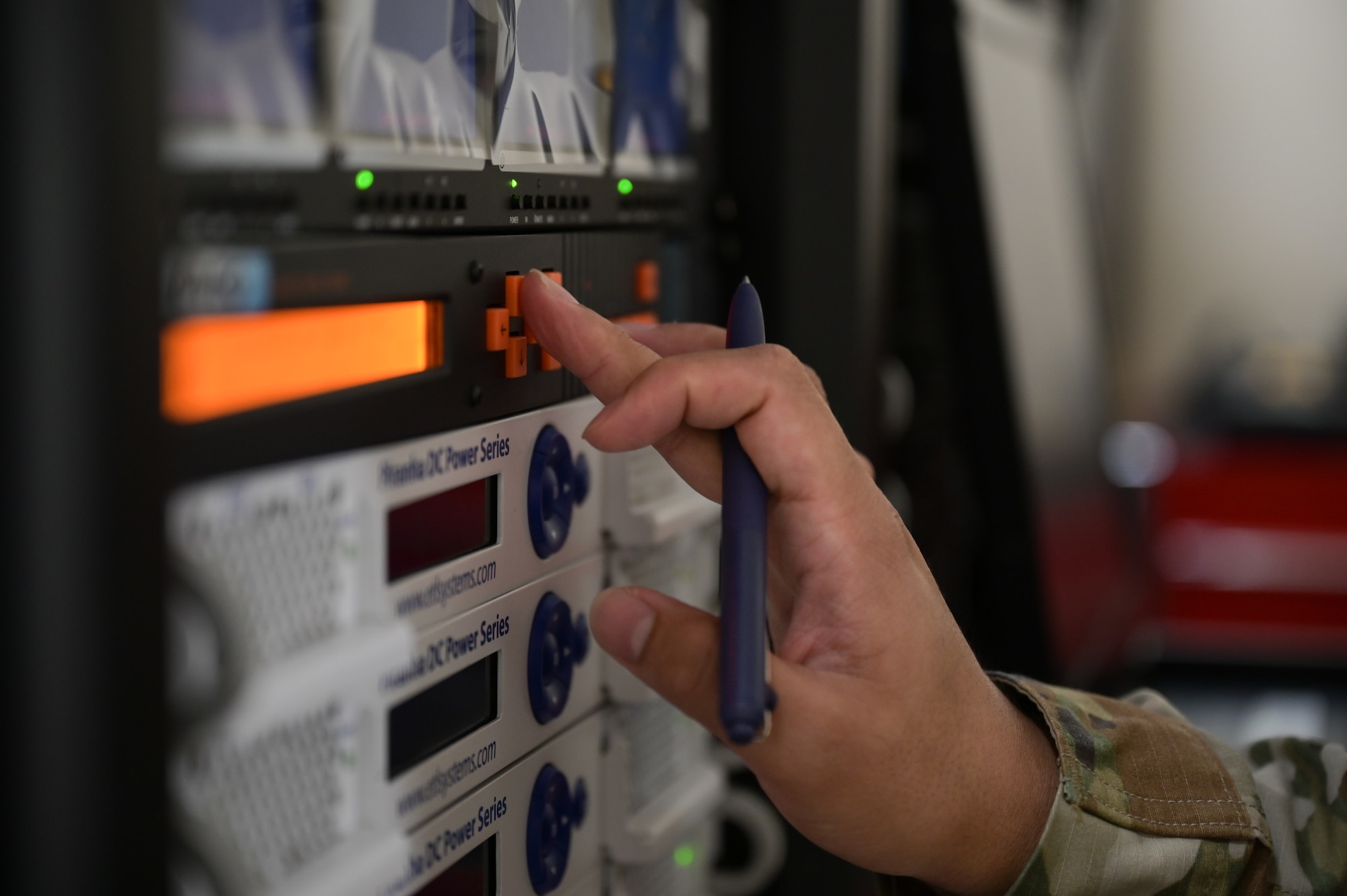 A hand pressing buttons on a computer server.