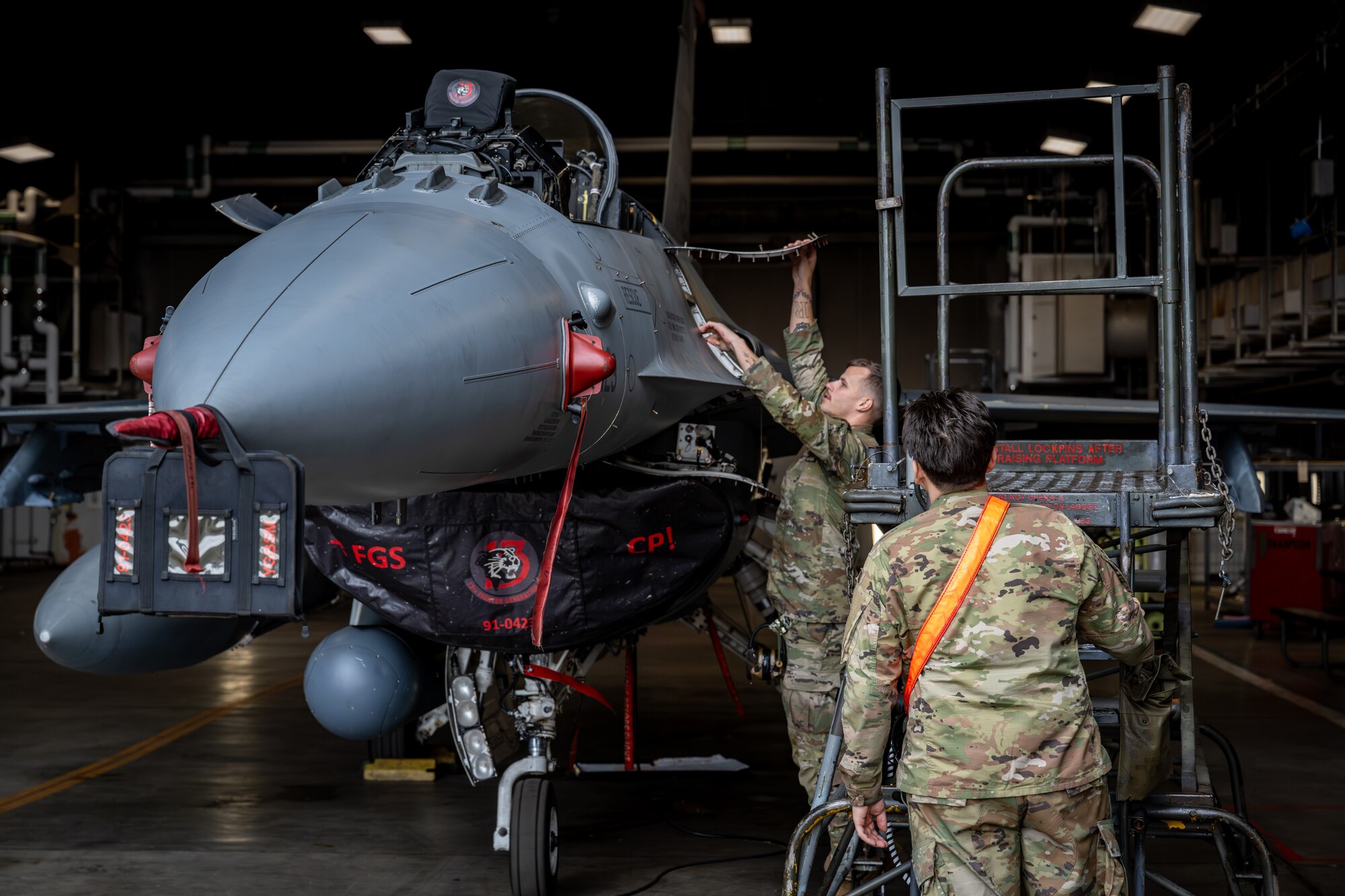 Airman performs maintenance on an F-16