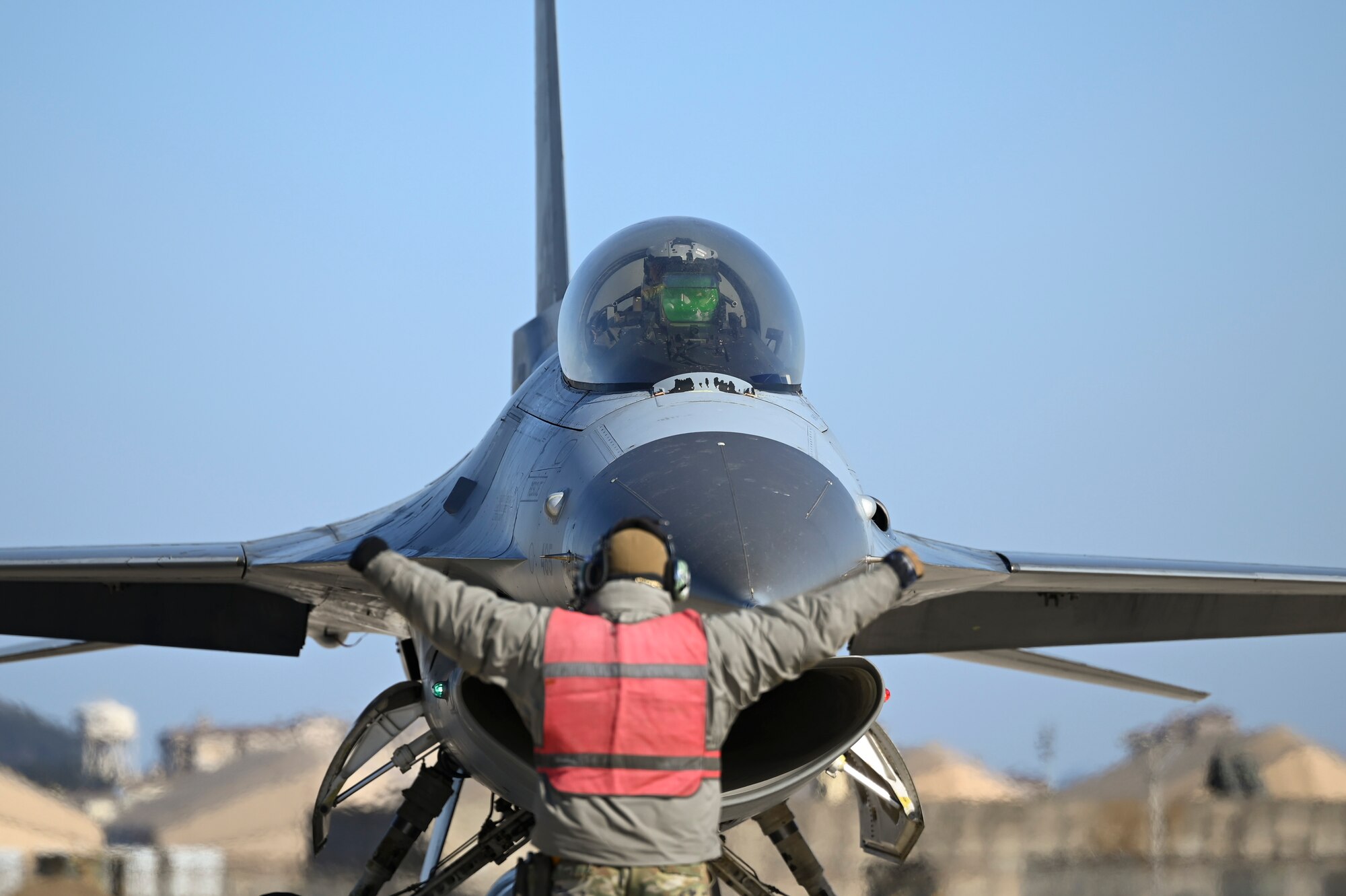 Airman 1st Class Chanon Absomtua, 35th Fighter Generation Squadron assistant dedicated crew chief, marshals an F-16 Fighting Falcon aircraft during an operational surge.