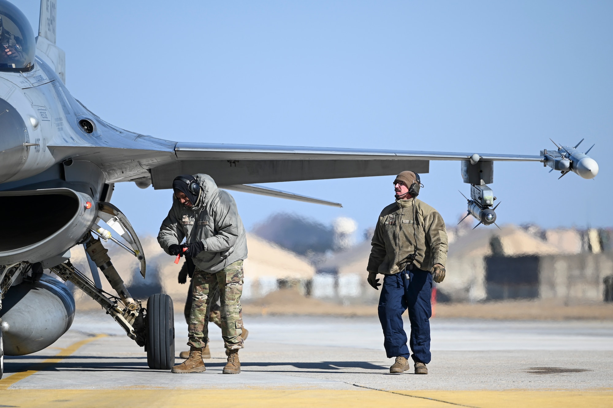 Airman 1st Class Jachonn Tisinger, left, 35th Fighter Generation Squadron weapons load crew member, and U.S. Air Force Staff Sgt. Christian Sanchez, 35th FGS dedicated crew chief, conduct hot pit refueling during an operational surge.