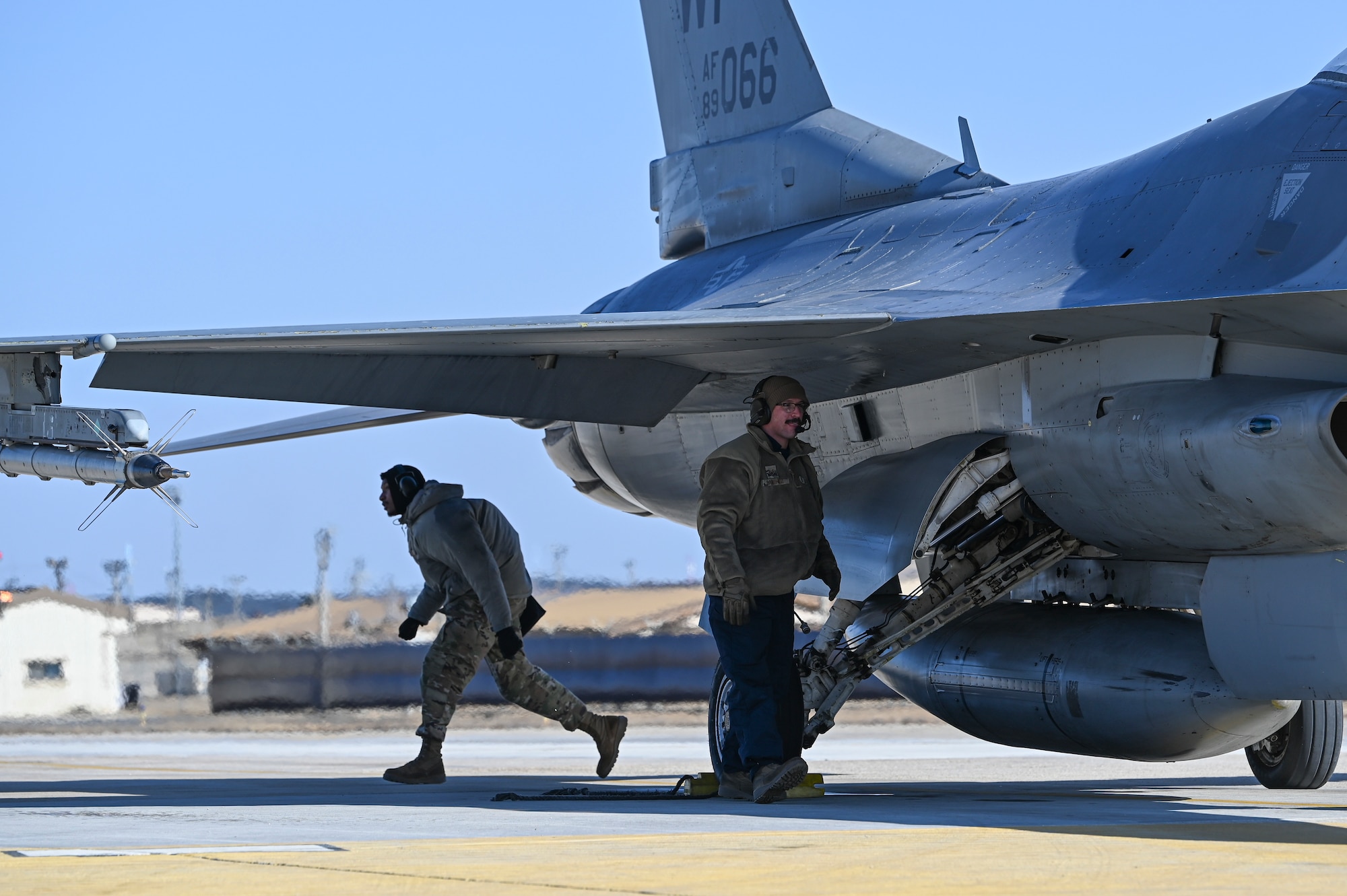 Airman 1st Class Jachonn Tisinger, left, 35th Fighter Generation Squadron weapons load crew member, and Staff Sgt. Christian Sanchez, 35th FGS dedicated crew chief, conduct hot pit refueling on an F-16 Fighting Falcon aircraft during an operational surge.