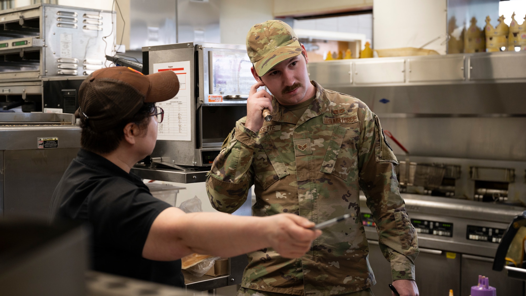 U.S. Air Force Senior Airman Aaron Burdette, 51st Civil Engineer Squadron pest manager, receives feedback from Sun-Cha, Cho, Army & Air Force Exchange Service restaurant manager, at Osan Air Base, Republic of Korea, April 1, 2025. Restaurants on base are inspected monthly to ensure a high quality of life and personnel health to positively impact readiness. (U.S. Air Force photo by Senior Airman Rome Bowermaster)