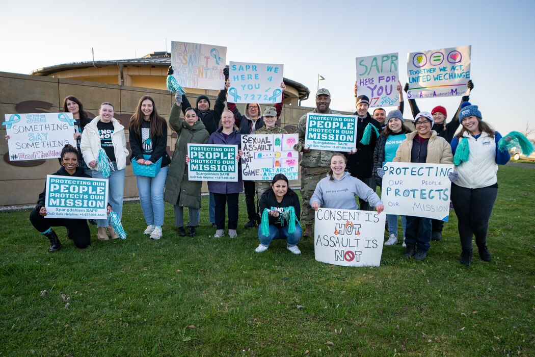 A group of people pose for a photo with Sexual Assault Awareness and Prevention Month signs.