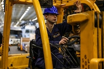 Aviation Machinist’s Mate 2nd Class Donald Stepp, assigned to aviation intermediate maintenance department aboard the world’s largest aircraft carrier, USS Gerald R. Ford (CVN 78), gives a hand signal while operating a forklift in the hangar bay, March 31, 2025.