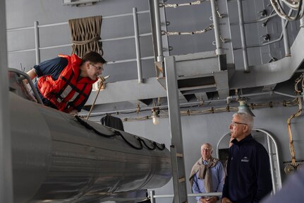 Boatswain’s Mate 3rd Class Brodie Winstead (left), assigned to deck department aboard the world's largest aircraft carrier, USS Gerald R. Ford (CVN 78), discusses the ship’s rigid hull inflatable boats (RHIB) with Distinguished Visitor (DV) Admiral (ret.) Samuel Locklear III during a tour of the ship, March 29, 2025.