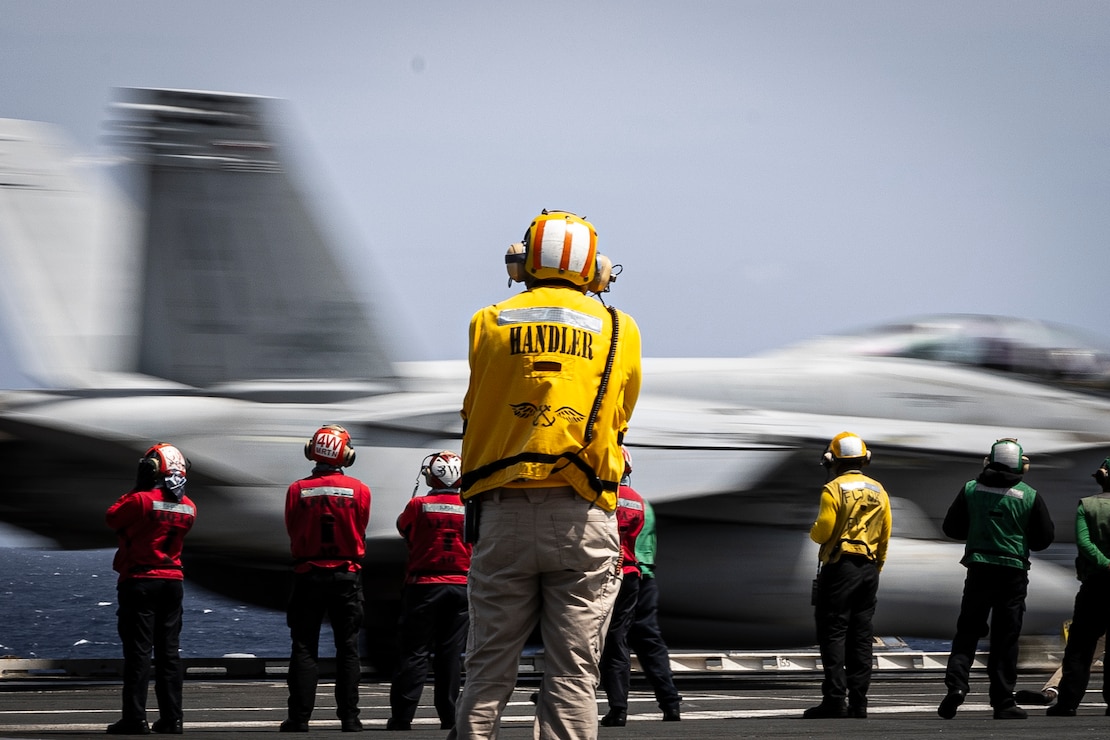Lt. Cmdr. Mark Rodriguez, aircraft handler aboard the world's largest aircraft carrier, USS Gerald R. Ford's (CVN 78) (center), observes the launch of an F/A-18F Super Hornet attached to the "Blacklions" of Strike Fighter Squadron (VFA) 213 on the flight deck, March 29, 2025.