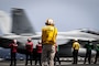 Lt. Cmdr. Mark Rodriguez, aircraft handler aboard the world's largest aircraft carrier, USS Gerald R. Ford's (CVN 78) (center), observes the launch of an F/A-18F Super Hornet attached to the "Blacklions" of Strike Fighter Squadron (VFA) 213 on the flight deck, March 29, 2025.
