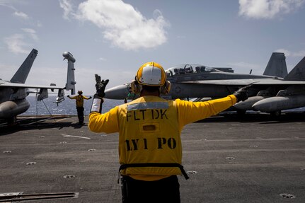 Aviation Boatswain's Mate (Handling) 1st Class Sam Smith (front) and Aviation Boatswain's Mate (Handling) 1st Class Alex Williams, both assigned to air department aboard the world's largest aircraft carrier, USS Gerald R. Ford (CVN 78), direct an F/A-18F Super Hornet attached to the "Blacklions" of Strike Fighter Squadron (VFA) 213 on the flight deck, March 29, 2025.