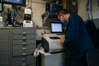Hospital Corpsman 2nd Class Connor Daniels, assigned to medical department aboard the world's largest aircraft carrier, USS Gerald R. Ford (CVN 78), observes the lens edger machine while making of a pair of eyeglasses in the eyeglass fabrication room, March 29, 2025.