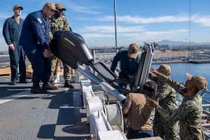Sailors transfer an elliptical machine aboard the Wasp-class amphibious assault ship USS Makin Island (LHD 8), during a working party, Dec. 2, 2024.
