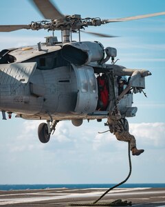 Sailors assigned to Explosive Ordnance Disposal Mobile Unit (EODMU) 12 fast rope from an MH-60S Sea Hawk, attached to the "Tridents" of Helicopter Sea Combat Squadron (HSC) 9, onto the flight deck of the world's largest aircraft carrier, USS Gerald R. Ford (CVN 78), March 28, 2025.
