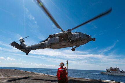 Sailors assigned to weapons department aboard the world's largest aircraft carrier, USS Gerald R. Ford (CVN 78), hook cargo to an MH-60S Sea Hawk, attached to the "Tridents" of Helicopter Sea Combat Squadron (HSC) 9, during a vertical replenishment (VERTREP) on the flight deck, March 27, 2025.